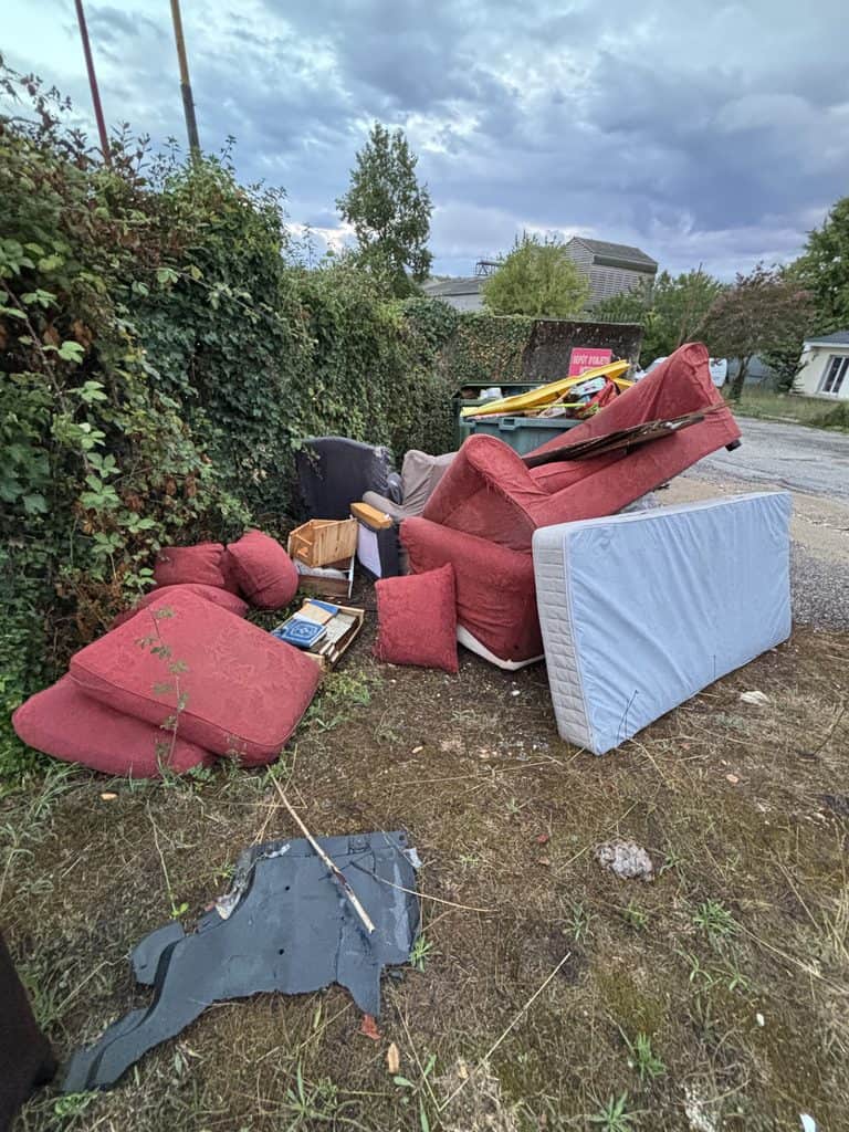 Déchets et meubles abandonnés dans un espace extérieur en zone résidentielle.