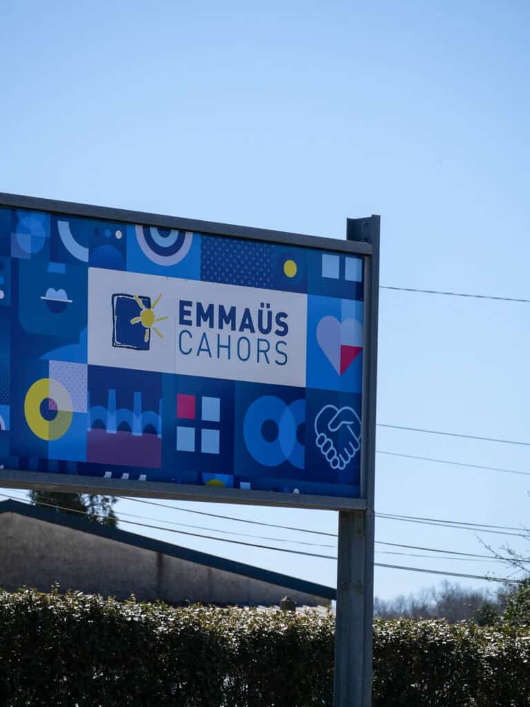 Panneau Emmaüs Cahors avec logo et motifs colorés.